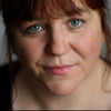 Headshot for Orla McGovern. A white-skinned, blue-eyed and red-haired woman looks at the camera closely.